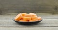 Black plate with thick slices carrots on woode table