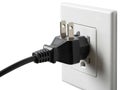 Black plug inserted into white wall outlet Royalty Free Stock Photo