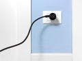 Black Plug in a Wall Socket on a Blue Wall