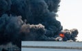 Black plumes of smoke from an accidental toxic industrial fire as seen from a behind a factory building