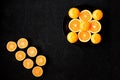 A composition of cut in halves oranges and tangerines on a black background