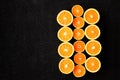 A composition of cut in halves oranges and tangerines on a black background