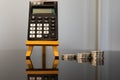 Black pocket calculator on Easel beside stack of coins Royalty Free Stock Photo