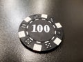 a black poker chip of 100 on a black table Royalty Free Stock Photo