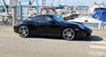 Black Porsche Cayman S parked outside a marina pier.