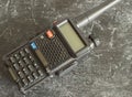 A black portable analog walkie-talkie on a dark concrete background