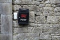 Black Postbox on a stone wall