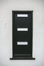 Black postbox in a white wall