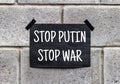 Black poster on gray brick wall. Banner with text STOP PUTIN STOP WAR. RUSSIAN WAR. Aggressive invasion