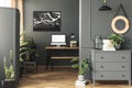 Black poster on grey wall above desk with mockup in home office interior with mirror. Real photo Royalty Free Stock Photo