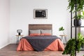 Black poster on the white wall of bedroom interior with king size bed with wooden headboard Royalty Free Stock Photo