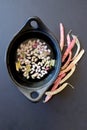 A black pot of fresh podded cranberry beans on a black background