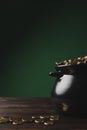 black pot of golden coins on wooden table on green st patricks