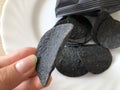 Black potato chips colored with food coal on white plate