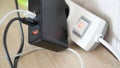 Black power adapter and illuminated white switch with red indicator connected on wooden desk surface Royalty Free Stock Photo