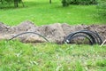 Black power cable is laid in a narrow trench in the grass across the garden, because it is a safer power supply than overhead