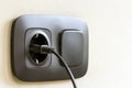 Black power cord cable plugged into european wall outlet on whit Royalty Free Stock Photo