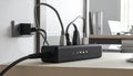Black power strip with multiple plugs and cables connected to a wall socket electrical outlet Royalty Free Stock Photo