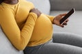 Black pregnant woman holding mobile phone with empty screen Royalty Free Stock Photo