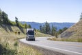 Black pro big rig semi truck transporting cargo in semi trailer climbing uphill on the winding mountain narrow road in Columbia Royalty Free Stock Photo