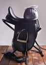 Black professional leather dressage saddle in complete with riding helmet and gloves puted at saddle rack travel