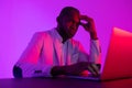 A black programmer works using a laptop computer. the man works at night.