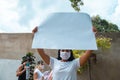 A black protester holding a banner with no writing on the outside, other people behind also holding empty signs