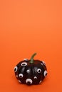 Black pumpkin with many eyes on orange background.