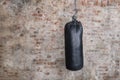 Black punching bag with grunge brick wall with blank space