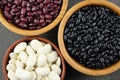 Black, purple and white dried beans in wooden bowls on a dark ru Royalty Free Stock Photo