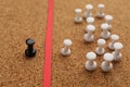 Black push pin separated from white ones by red strip in cork board, closeup. Racism concept Royalty Free Stock Photo