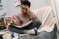 Black puzzled boy doing homework while sitting on sofa Royalty Free Stock Photo