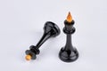 Black queen chess piece stands near fallen chess piece. Royalty Free Stock Photo