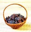 Black raisin in wicker basket on matting