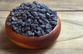 Black raisins in a bowl on a wooden table. Royalty Free Stock Photo