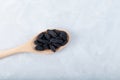 Black raisins in wooden spoon on grey background. Dried dehydrated grapes fruit. Selective focus, copy space Royalty Free Stock Photo