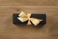 Black rectangle gift box with champagne color ribbon bow on wooden oak table from above Royalty Free Stock Photo