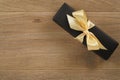 Black rectangle gift box with champagne color ribbon bow on wooden oak table from above Royalty Free Stock Photo