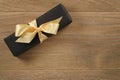 Black rectangle gift box with champagne color ribbon bow on wooden oak table from above Royalty Free Stock Photo