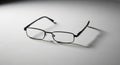 Black rectangular eyeglasses with thin metal frames resting on a smooth white surfac Royalty Free Stock Photo