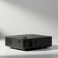 Black, rectangular portable projector sits on a white surface with a soft shadow. It Royalty Free Stock Photo