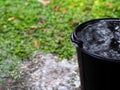 Black recycling plastic bucket on the floor outdoor surrounding with green area environment,  raindrops splash and reflection o Royalty Free Stock Photo