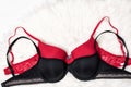 Black and red bra on white fur. Flat lay. Fashion concept Royalty Free Stock Photo