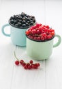 Black and red currant in tea cups on a white wooden table Royalty Free Stock Photo