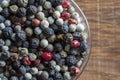 Black, red and white peppercorns in bowl on a wooden background. Mix of different peppers. Top view, closeup Royalty Free Stock Photo