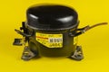 Black refrigerator compressor on yellow background