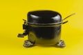 Black Motor-Compressor of the refrigerator on a yellow backgroun Royalty Free Stock Photo