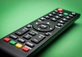 Black Remote Control with Colorful Buttons on Green Background Royalty Free Stock Photo