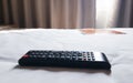 black remote tv controller on white bed with curtain background Royalty Free Stock Photo