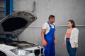 Black repairman shows the client the engine of a car